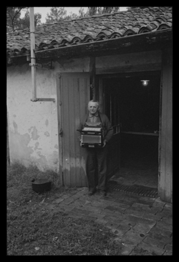 Henri Roumegoux devant la porte de sa maison tenant son accordéon (French) thumbnail