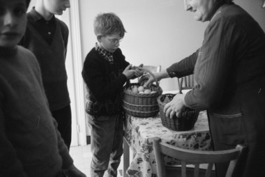 A l'intérieur d'une maison. Roulée des œufs du Samedi saint : Une personne visitée donne des oeufs aux enfants. la vignette