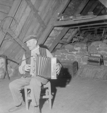 Au premier étage du buron, Monsieur Cayla joue de l'accordéon la vignette