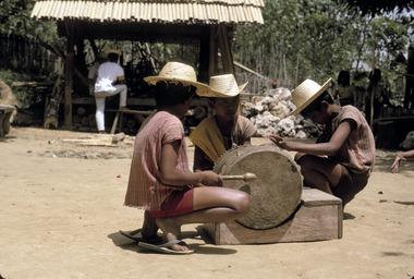 Trois enfants frappant un tambour., Three children beating a drum. (anglais), Tiga anak menabuh gendang.  (indonésien) la vignette
