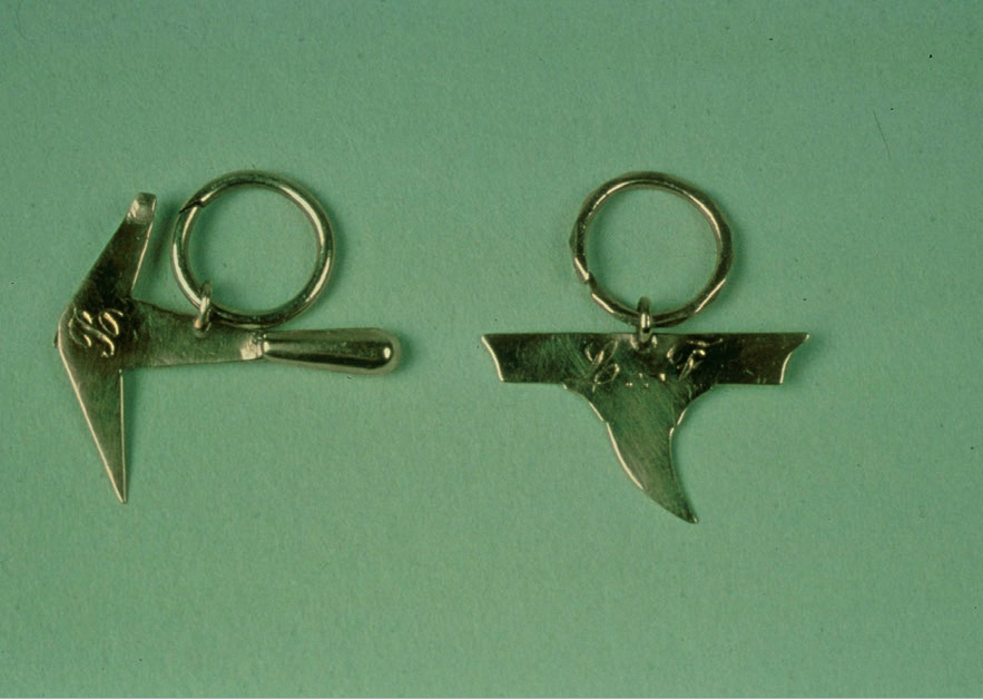 Figure 1 – Joints (anneaux d'oreille) de
          compagnons couvreurs avec outils suspendus (marteau et enclumette),
          19 siècle (coll. Musée du Compagnonnage de
          Tours).