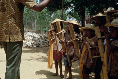 Child playing a monophonic horn (pompang)., Enfant jouant une trompe monophone pompang. (French), Seorang anak memainkan alat musik tiup satu nada pompang. (Indonesian) thumbnail