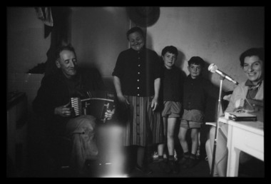 Gabriel Pioton jouant de l'accordéon, entouré de la famille Marquefave et de Madame Andral la vignette