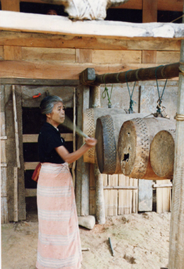 Une femme joue de quatre tambours suspendus, Mamasa, 1996., A woman plays four hanging drums, at Mamasa. (anglais), Seorang perempuan memainkan empat gendang yang digantungkan, di Mamasa. (indonésien) la vignette
