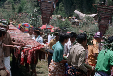 Les mâts bate arrivent un à un sur le « marché » (pasa')., The bate masts arrive one by one on the ‘market’ (pasa'). (anglais), Bendera bate tiba satu per satu di atas “pasar” (pasa’). (indonésien) la vignette