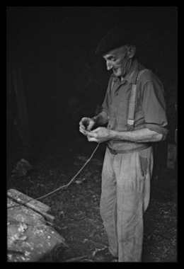 Léonce Mano dans son atelier confectionnant un rhombe. Confection du nœud de la corde la vignette