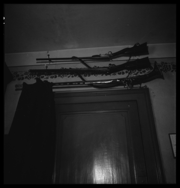 Chez Monsieur Louis Lafouge à 9h. Trois fusils de chasse au-dessus de la porte d'entrée de la cuisine la vignette