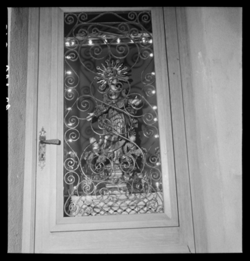 Décoration religieuse derrière une porte en fer forgé la vignette