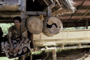 Au grenier à riz, suspendu par deux, Pangleon, 1993., A pair of drums hanging from a rice rice granary. Pangleon, 1993. (anglais), Di lumbung padi, diikatkan sepasang-sepasang. Pangleon, 1993. (indonésien) la vignette